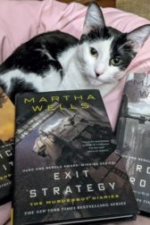 Black and white cat surrounded by three books, Artificial Condidtion, Exit Strategy, and Rogue Protocol