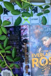 The cover of the book "The Everlasting Rose" by Dhonielle Clayton with branches of a rose bush above and to the side of the book.