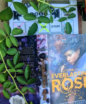 The cover of the book "The Everlasting Rose" by Dhonielle Clayton with branches of a rose bush above and to the side of the book.
