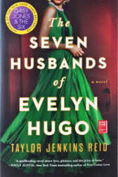Book cover: The Seven Husbands of Evelyn Hugo. A woman stands in a glamorous green dress. We cannot see her face.