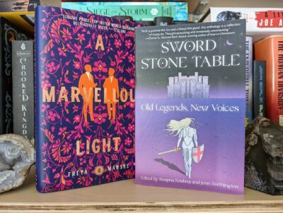 The books "A Marvellous Light" by Freya Marske and "Sword, Stone, Table: Old Legends, New Voices" anthology standing next to each other.