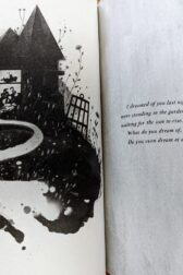 A book open with on one page an ink drawing of a house with a broken window and below are figures suggesting a face and a hand. On the next page the quote, "I dreamed of you last night. Isn't that strange? I dreamed that you were standing in the garden, looking up, I dreamed that you were waiting for the sun to rise. It never came. What do you dream of, I wonder? Do you even dream at all?"