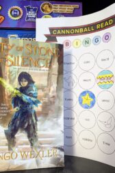 The book, "City of Stone and Silence" by Django Wexler standing next to a book bingo card.