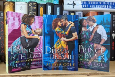 Three books standing next to each other on a bookshelf. "A Princess in Theory" "A Duke by Default" "A Prince on Paper" all written by Alyssa Cole.