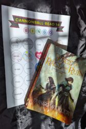 The book, "Siege of Rage and Ruin" by Django Wexler lying on top of a book bingo card. Shadows stripe across the image.