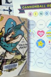 The Japanese manga, "Witch Hat Atelier" volume one next to a book bingo card.