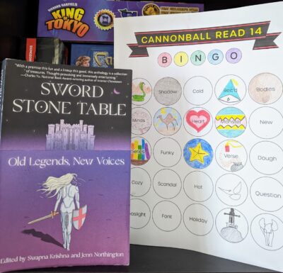 The book,"Sword Stone Table: Old Legends, New Voices" edited by Swampna Krishna and Jenn Northington next to a book bingo card.
