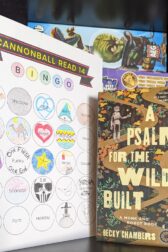 The book, "A Psalm for the Wild-Built" by Becky Chambers standing next to a mostly filled out book bingo card.