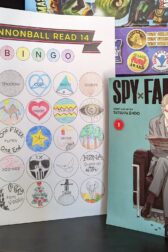 The manga, "Spy x Family volume one" by Tatsuya Endo standing next to a nearly complete book bingo card.