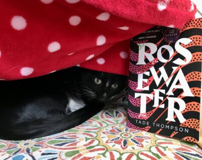 cat under blanket with copy of Rosewater by Tade Thompson