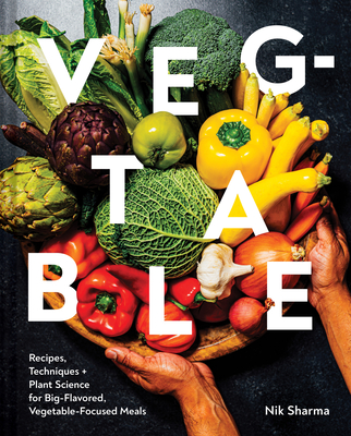 Birds Eye shot off a basket full of vegetables being placed on a table by brown hands with the letters of the title, Veg-table, superimposed. In the lower left corner, text reads “recipes, techniques, and plant science for big-flavored, vegetable-focused meals. In the lower right corner is the author’s name, Nik Sharma 