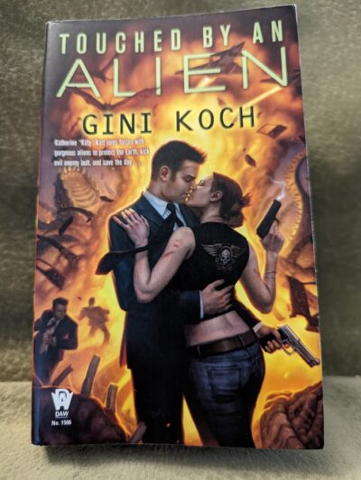 The cover of the book "Touched by an Alien" by Gini Koch showing two people passionately embracing and kissing.