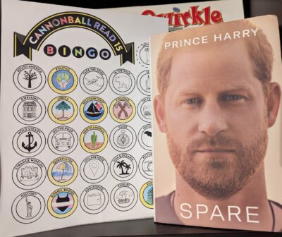 The book, "Spare" by Prince Harry standing next to a partially complete book bingo card.