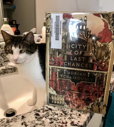 cat in the sink with the book City of Last Chances on the edge