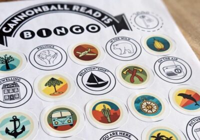 An image of a black and white printout of the Cannonball Read 15 Bingo card with some badges filled in with matching stickers.