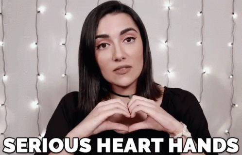A gif of a woman making a heart with her hands and saying “serious heart hands”
