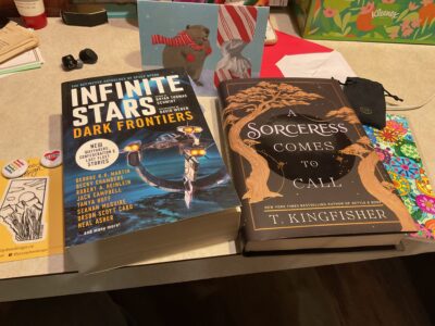 Gifts from KRussell. A beautiful Alberta shaped nature sticker, two reading pins, Infinite Stars: Dark Frontiers and anthology of space operas with selections from Becky Chambers and Seanan McGuire, T. Kingfisher’s A Sorceress Comes to Call, a hand colored bookmark, and a card with a beaver wearing a festive scarf next to a candy cane chewed the way a beaver would chew a tree.