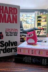 Three stacked books. "We solve murders" by Richard Osman, "Ink, blood, sister, scribe" by Emma Torzs, and a Kindness Journal