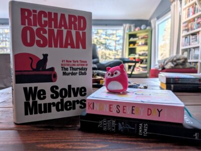 Three stacked books. "We solve murders" by Richard Osman, "Ink, blood, sister, scribe" by Emma Torzs, and a Kindness Journal